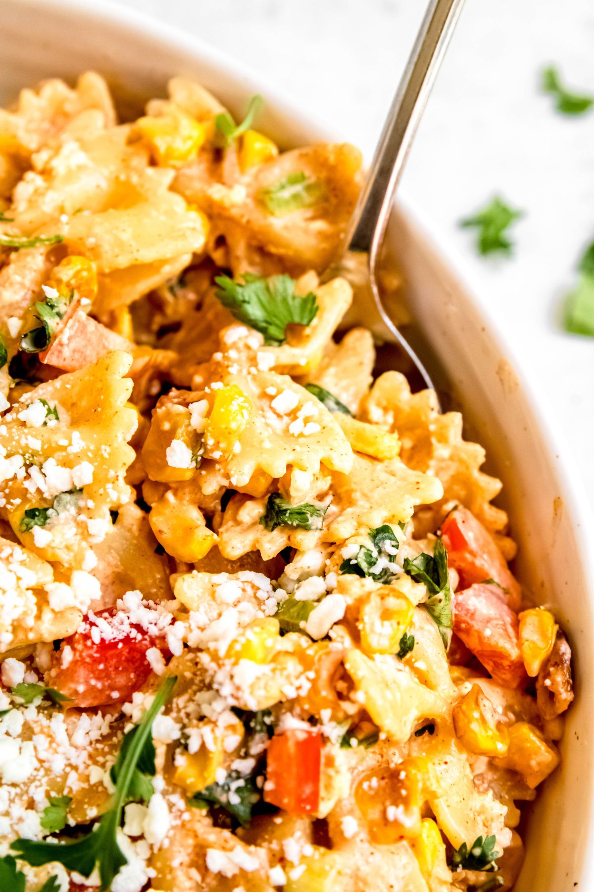closeup shot of a bowl of Mexican street corn pasta salad showing the creamy dressing and vibrantly colored veggies.