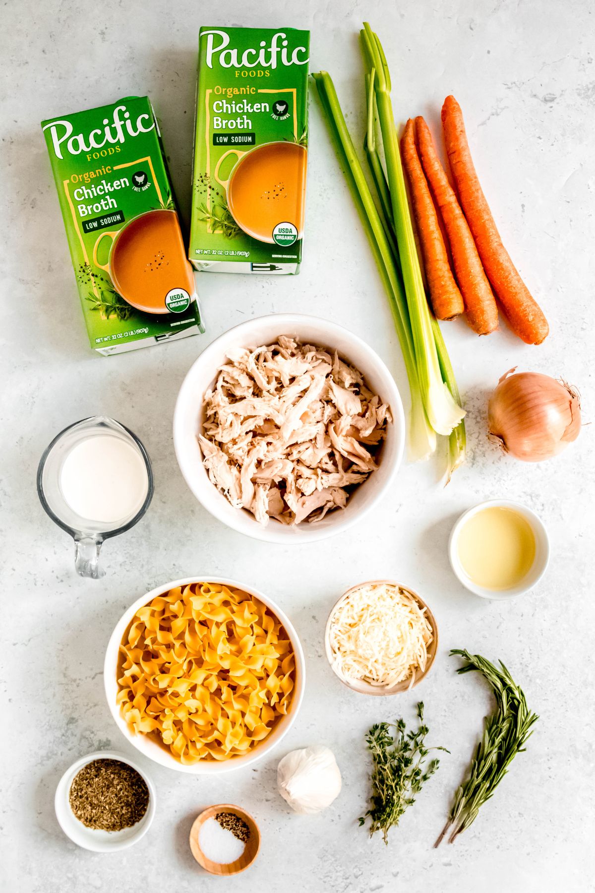 ingredients needed to make creamy leftover turkey noodle soup measured out into bowls on a white table.