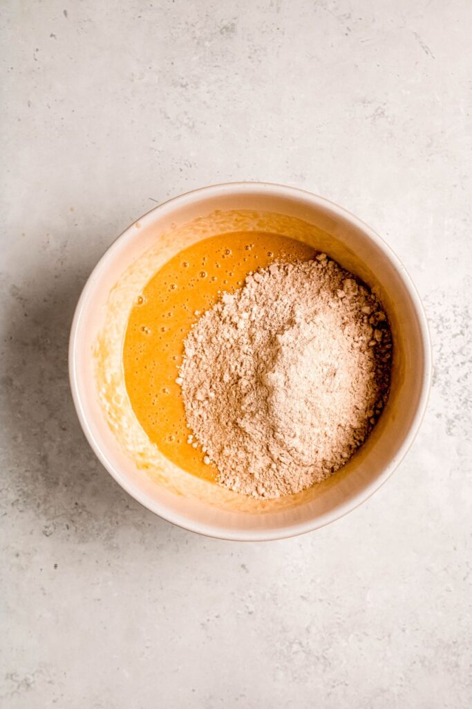 Adding the dry to the wet ingredient in a mixing bowl.