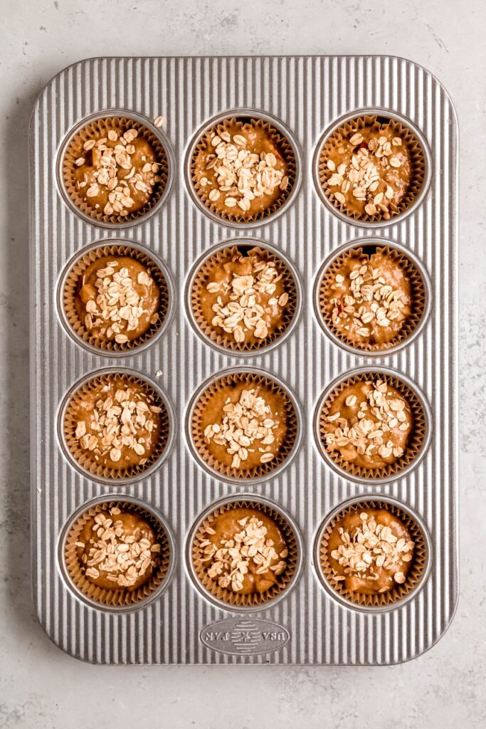The muffin batter scooped into the muffin tray with its streusel.