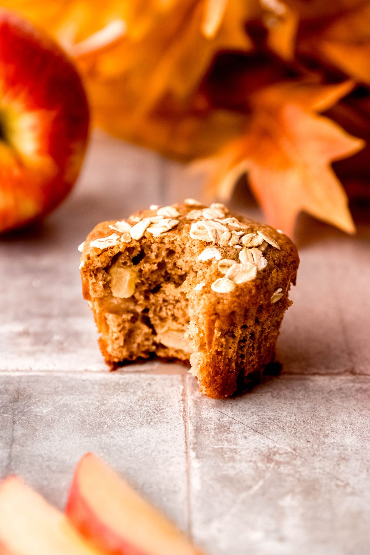 A slightly angled shot of apple cinnamon protein muffins on the counter with a bite taken out of them.