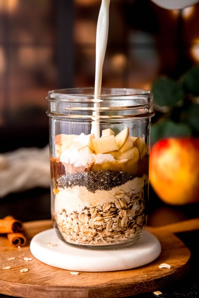 action shot of milk being poured into the jar with the oats and other ingredients.