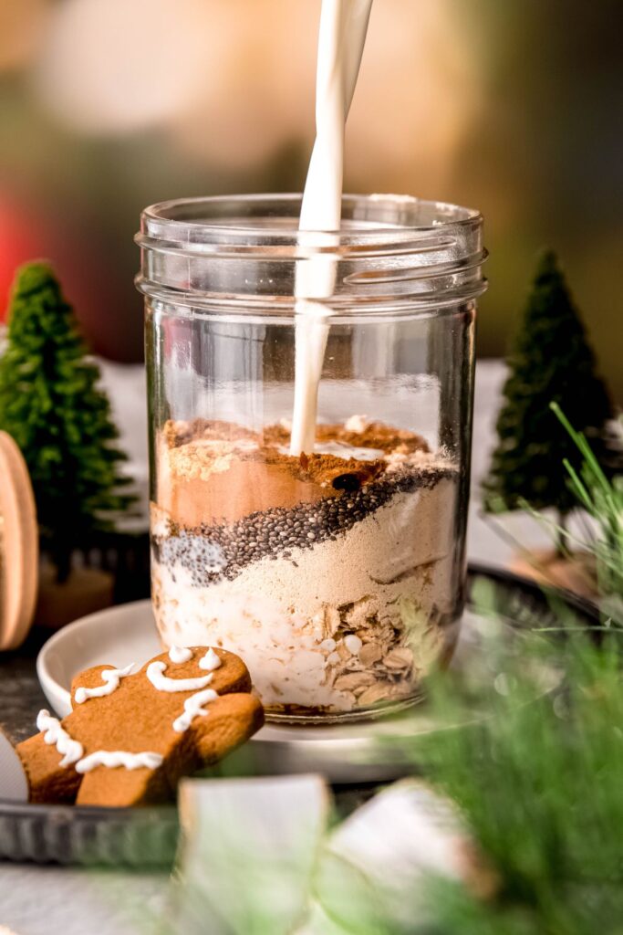 action shot of milk being poured into the mason jar with the gingerbread oat protein mixture.