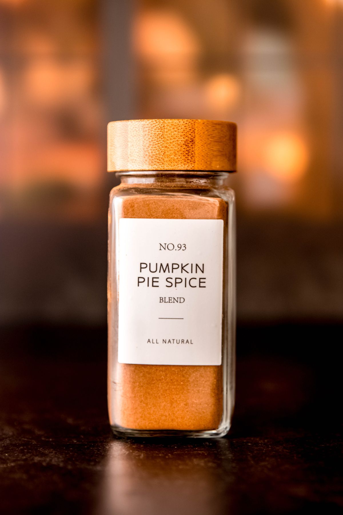 clear glass spice bottle with a wooden top and a white label that reads "number 93 pumpkin pie spice blend — all natural" that is filled with homemade pumpkin spice seasoning.