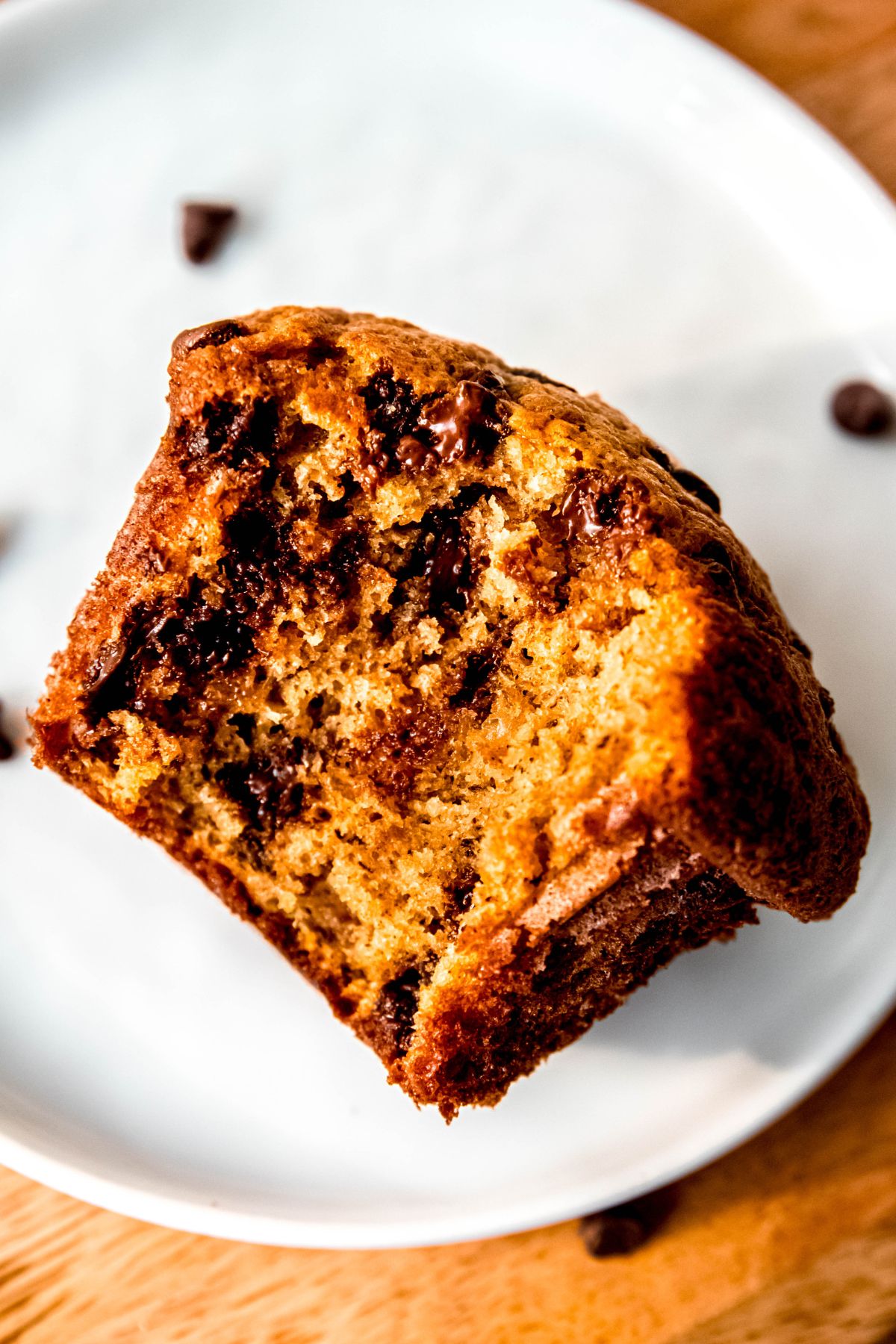 protein powder banana chocolate chip muffin with a big bite taken out and tipped on its side to show the fluffy interior crumb and melty chocolate chips.