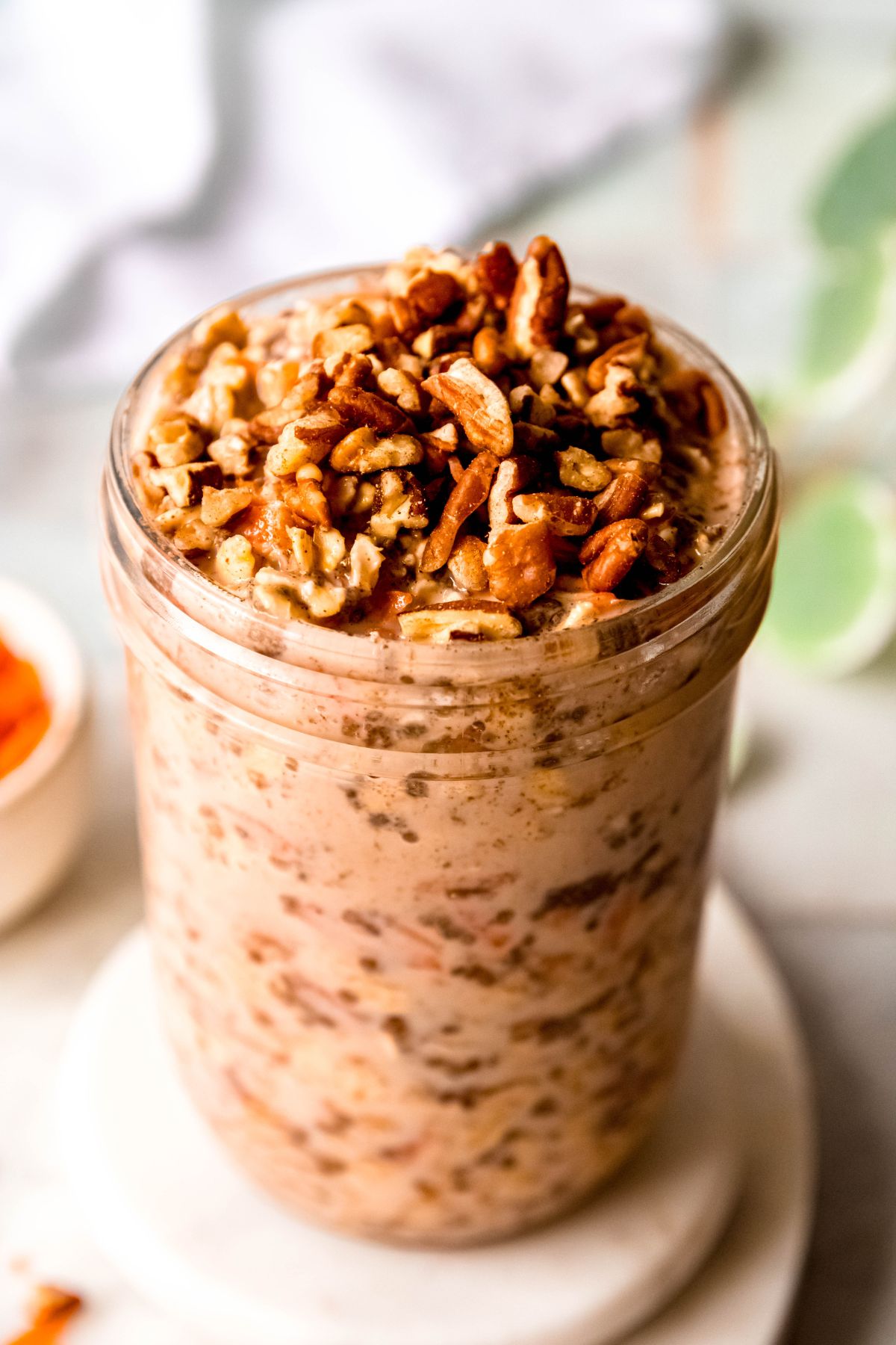 closeup 45 degree angle shot of a jar of carrot cake overnight protein oats on a white table.