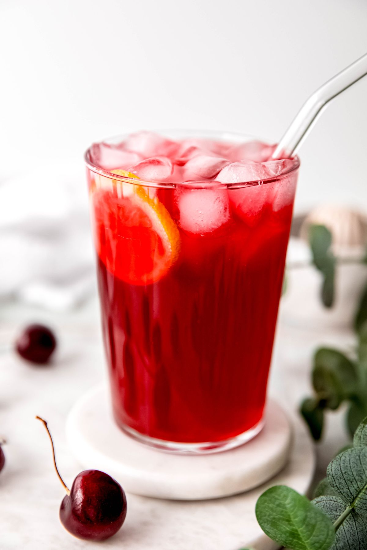 clear glass straw stuck into a glass of homemade black cherry lemonade.