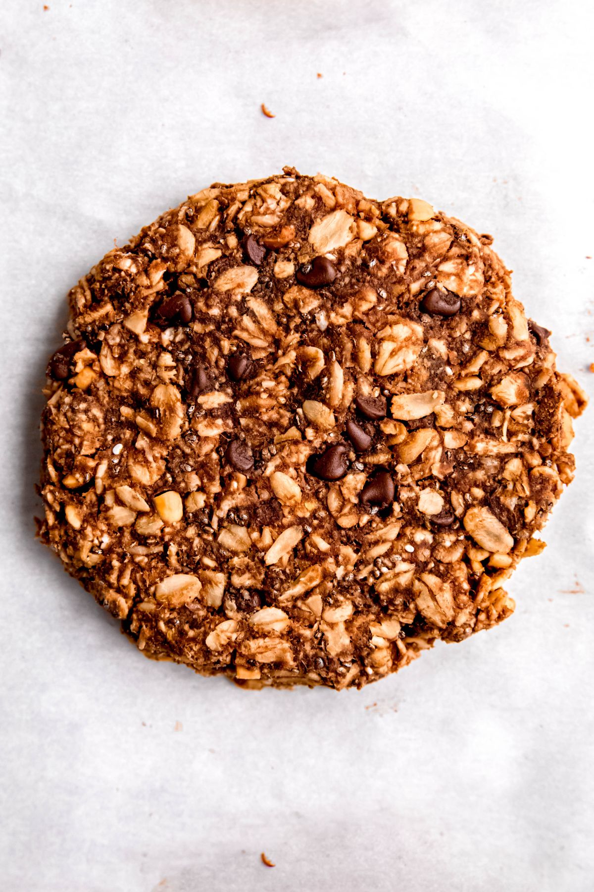closeup shot of a homemade chocolate protein powder oatmeal cookie on a white table.