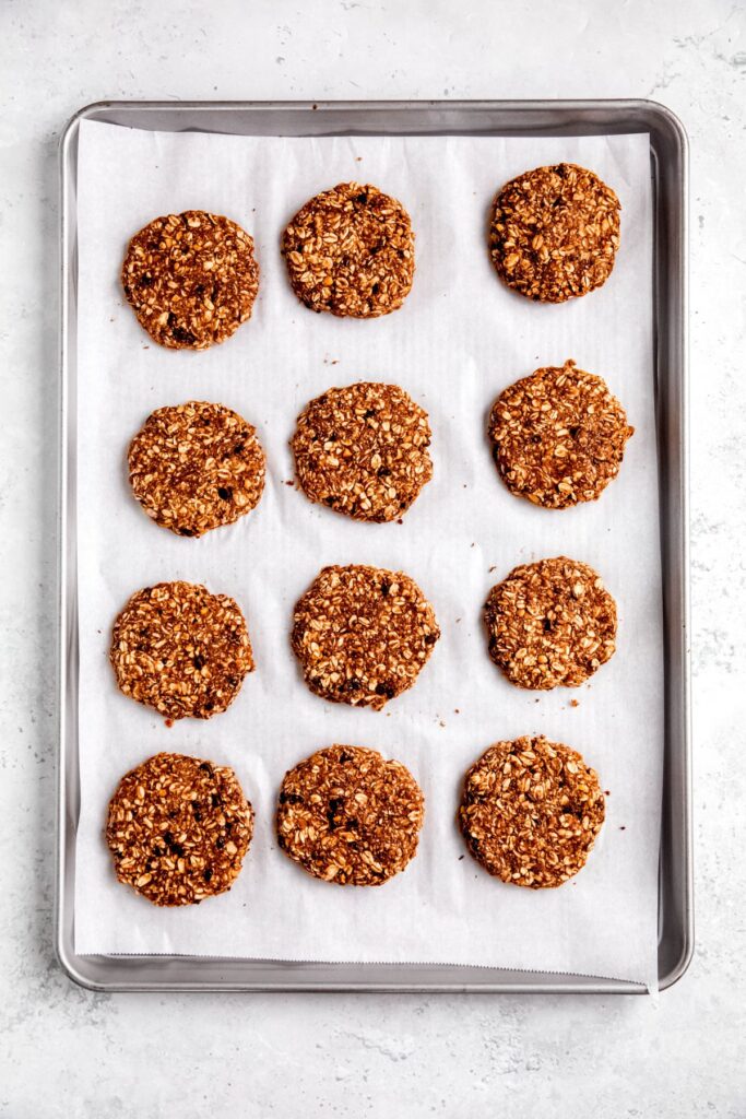12 chocolate chip oatmeal chocolate protein cookies on a parchment lined baking sheet.