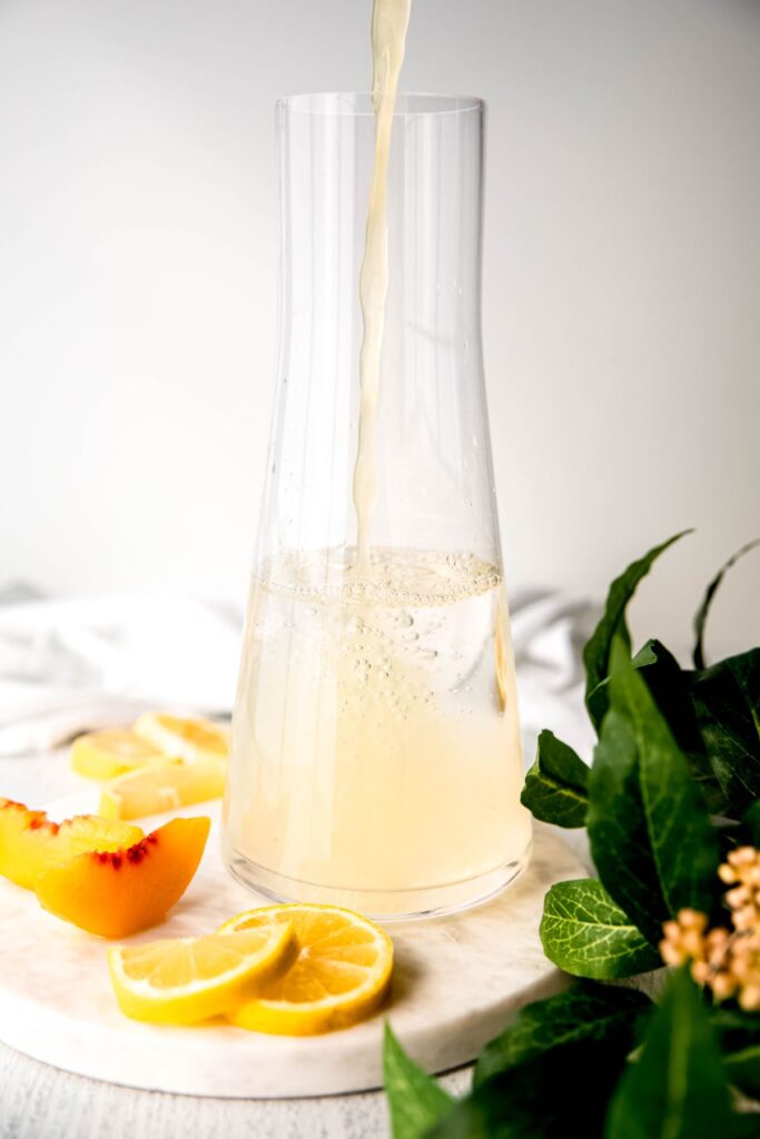 fresh lemon juice being added to the pitcher of water.