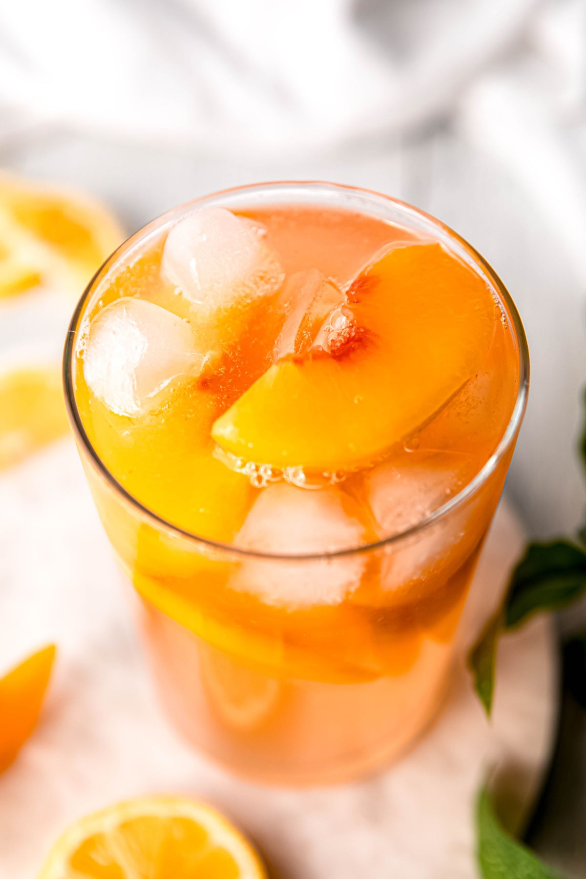 45 degree overhead shot looking down into a glass of peach-flavored lemonade garnished with fresh peach slices.