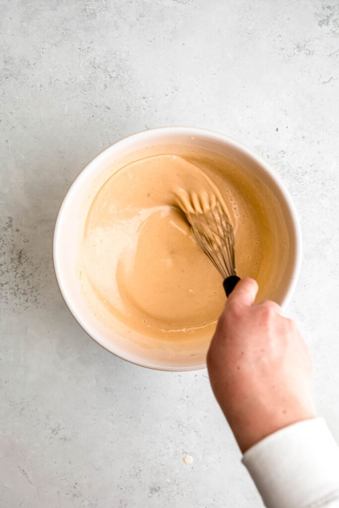A hand whisking the wet ingredients.