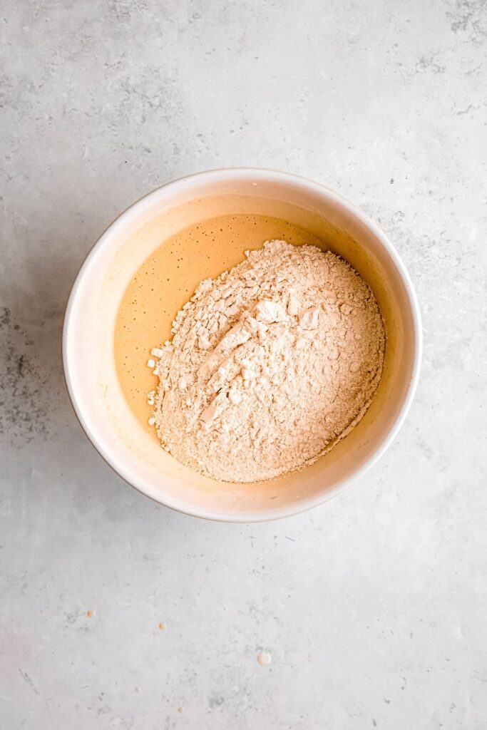 A bowl of whisked wet ingredients with the dry ingredients added.