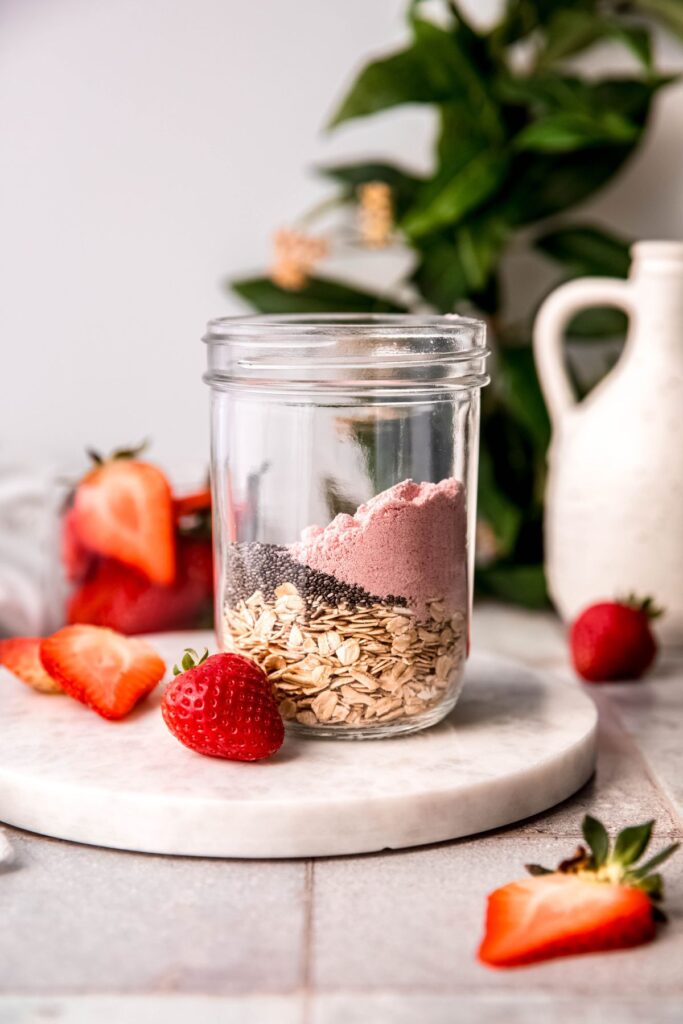 dry ingredients for making strawberry overnight protein oats layered in a clear mason jar.
