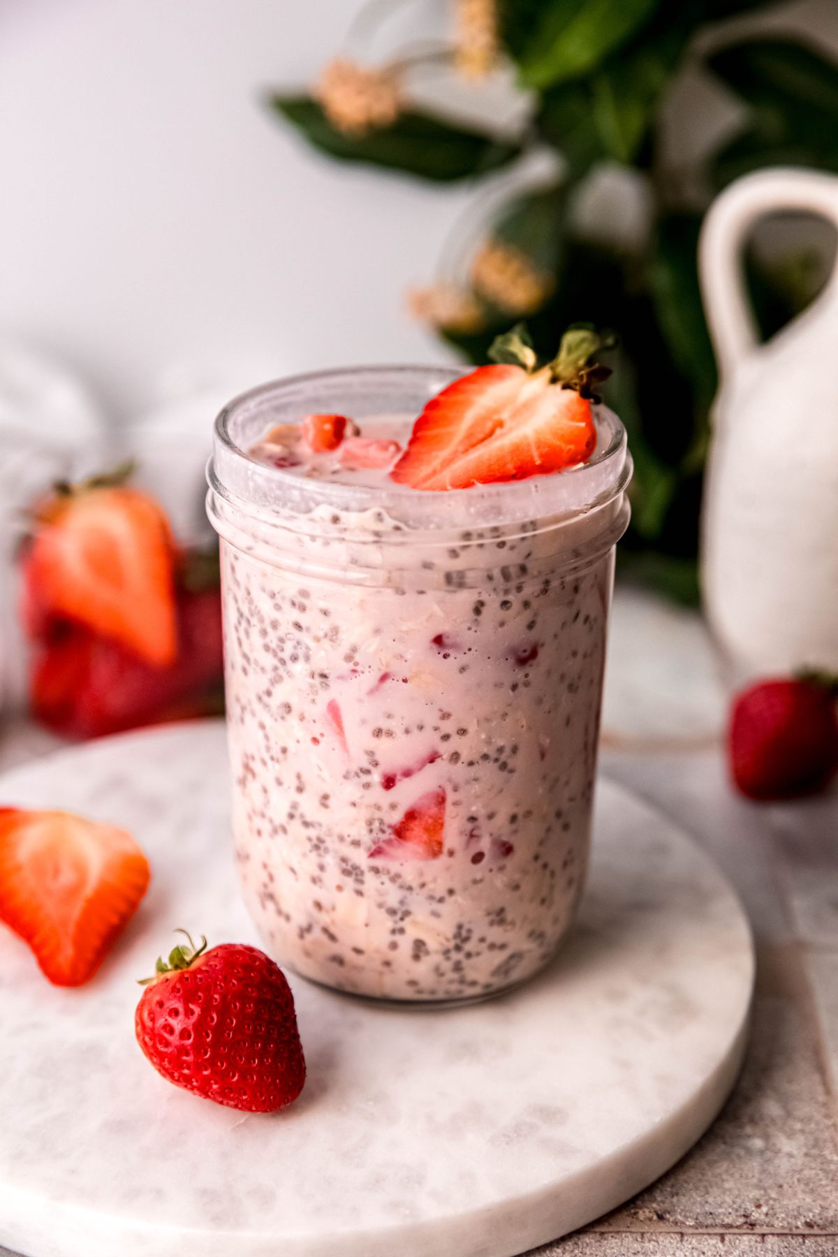 8 ounce mason jar filled with strawberry protein overnight oats topped with half a fresh strawberry.
