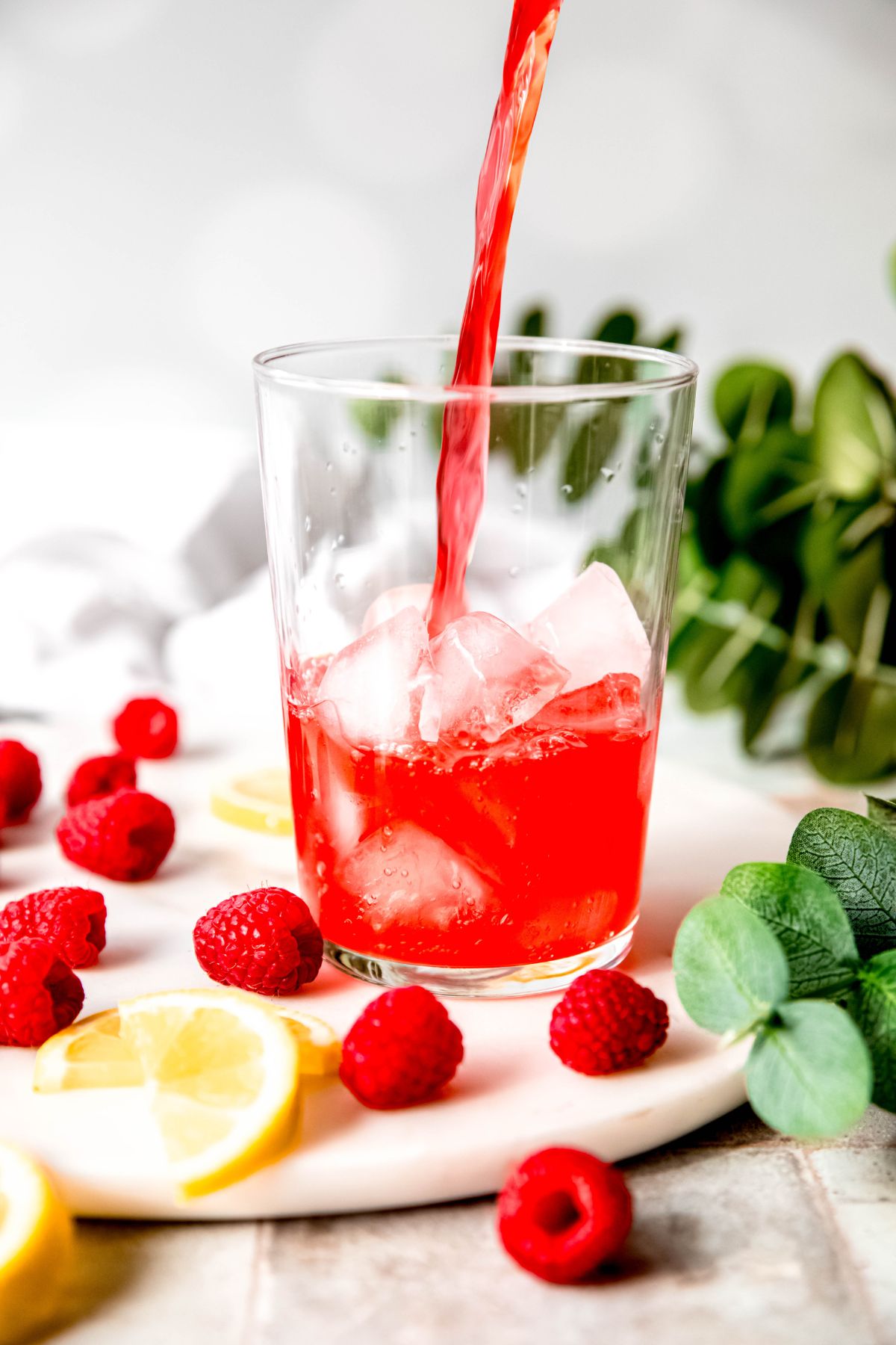 action shot of raspberry lemonade being poured into a glass of ice.