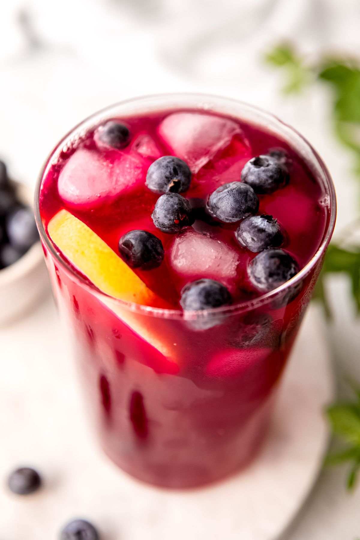 45 degree angle downward shot of homemade blueberry lemonade with blueberries and a round of lemon floating in the glass.