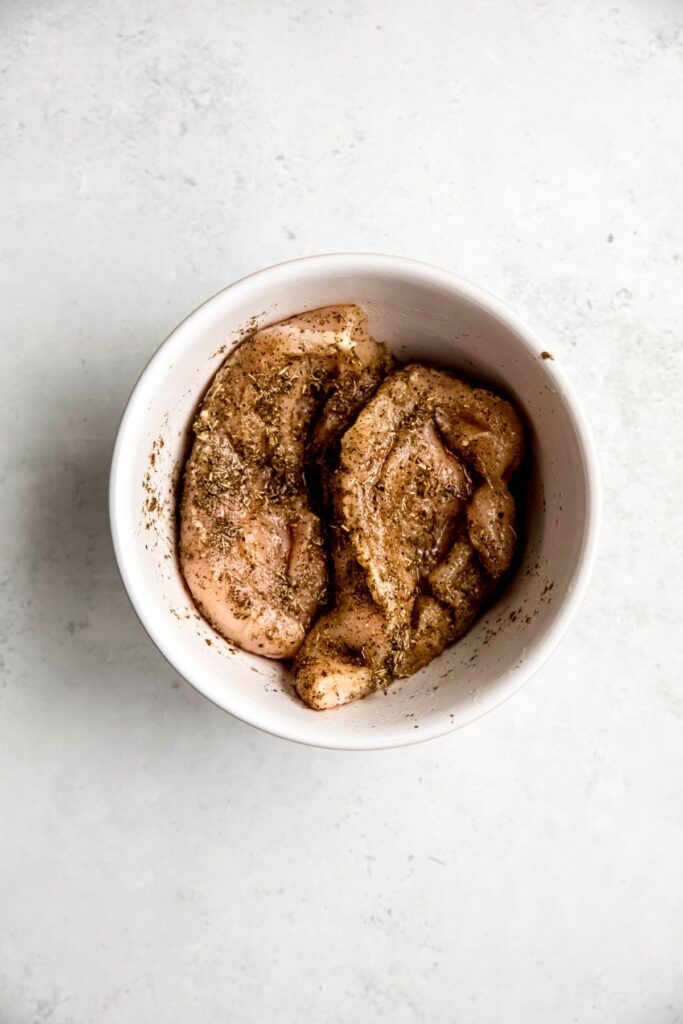Chicken marinating in a bowl.