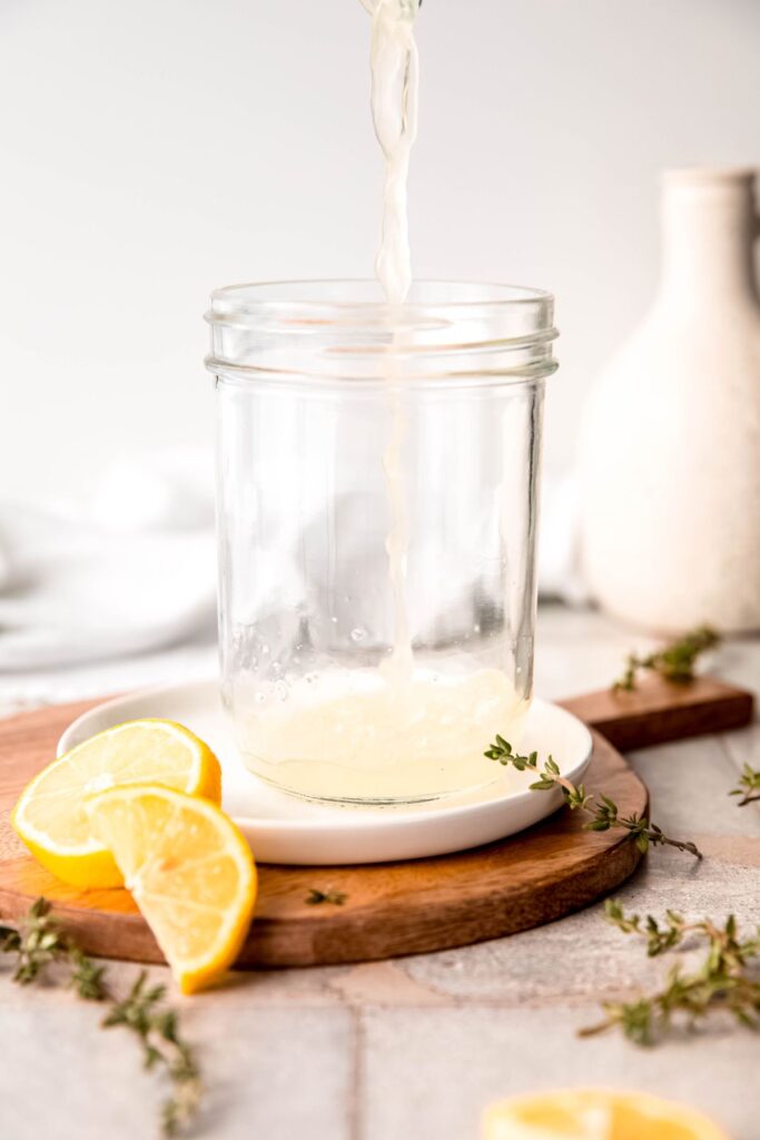 action shot of fresh lemon juice being squeezed into a mason jar.