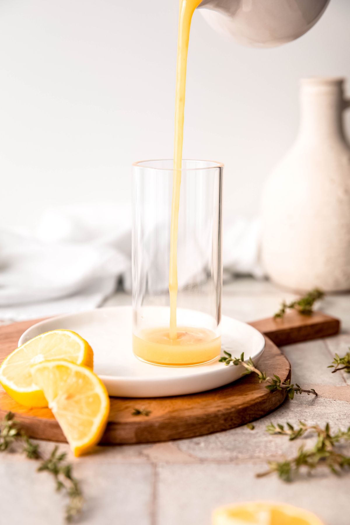 action shot of honey lemon vinaigrette being poured into a clear glass.