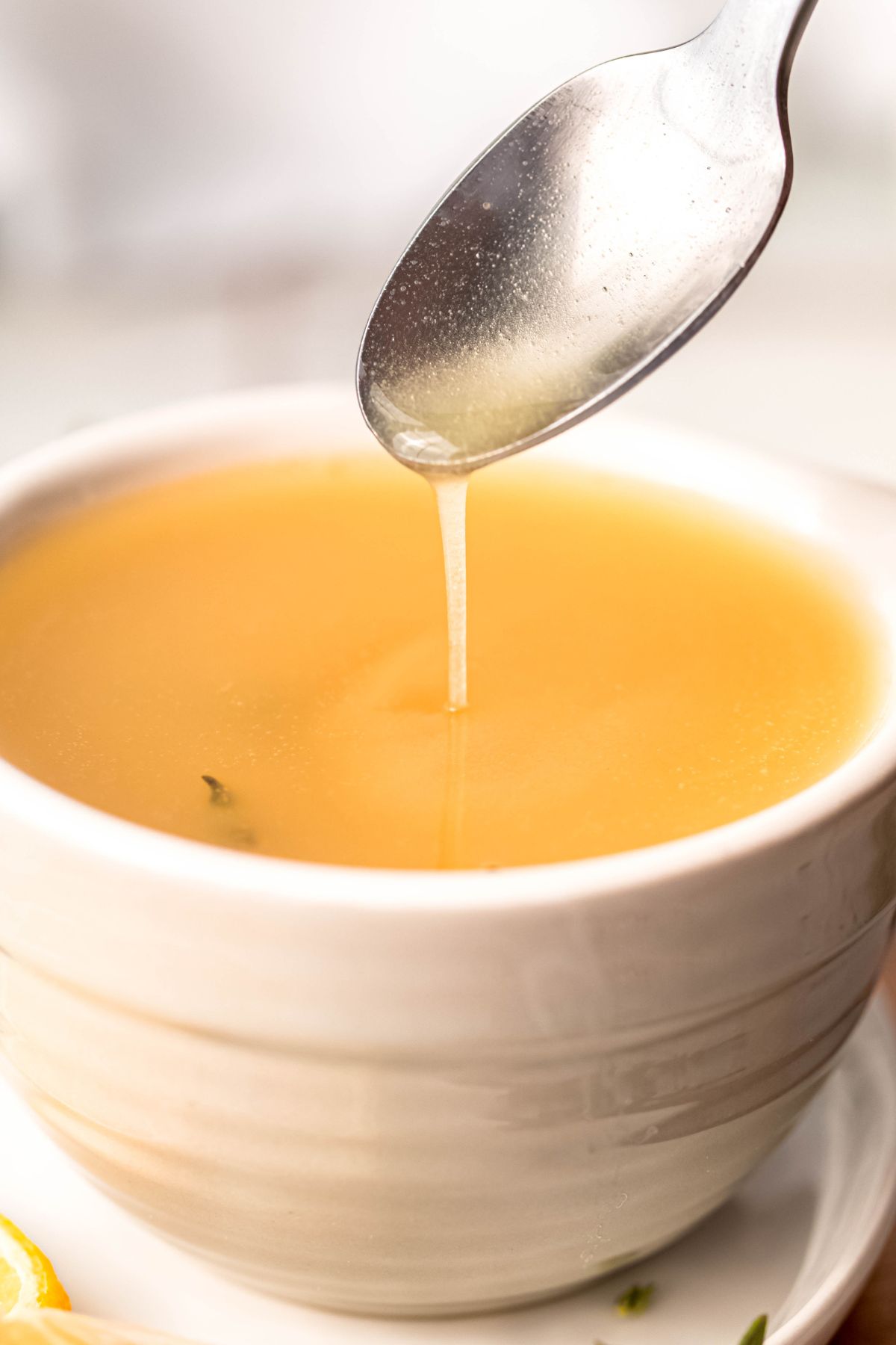 silver spoon drizzling fresh lemon vinaigrette into a white bowl.