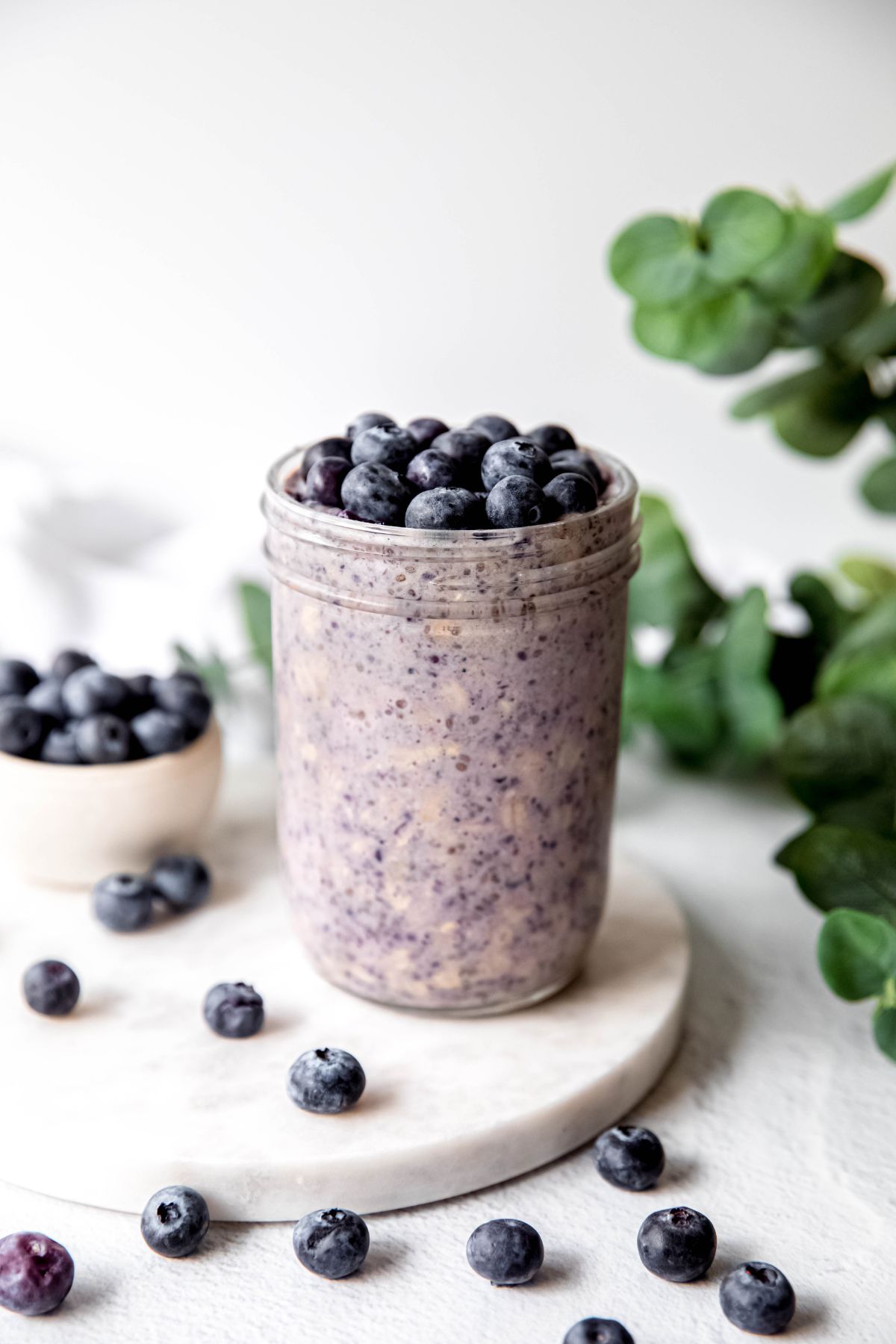 An elevated shot of a glass of high protein overnight blueberry oats.