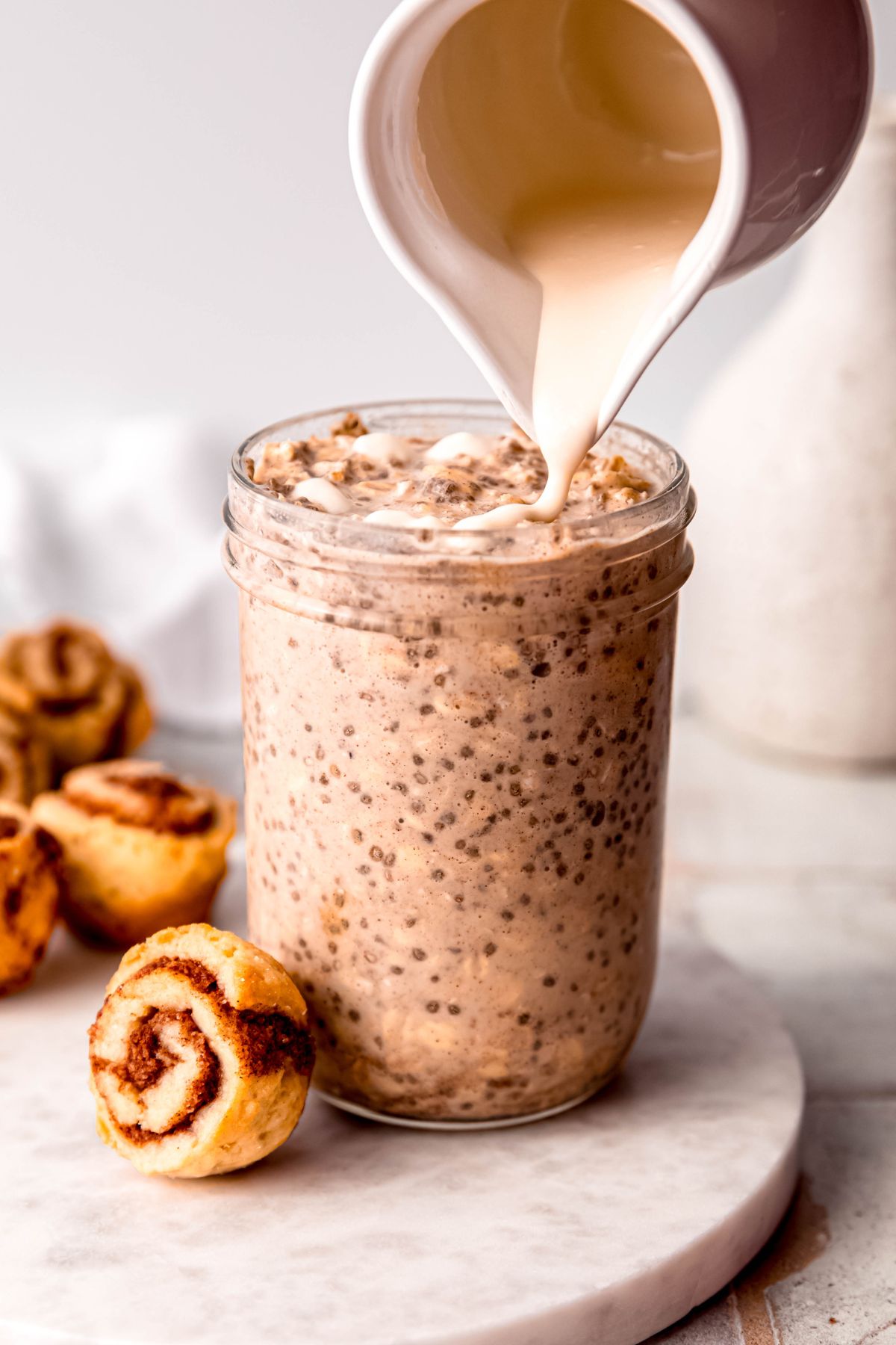 Pouring the protein drizzle over the cinnamon roll overnight oats before serving.