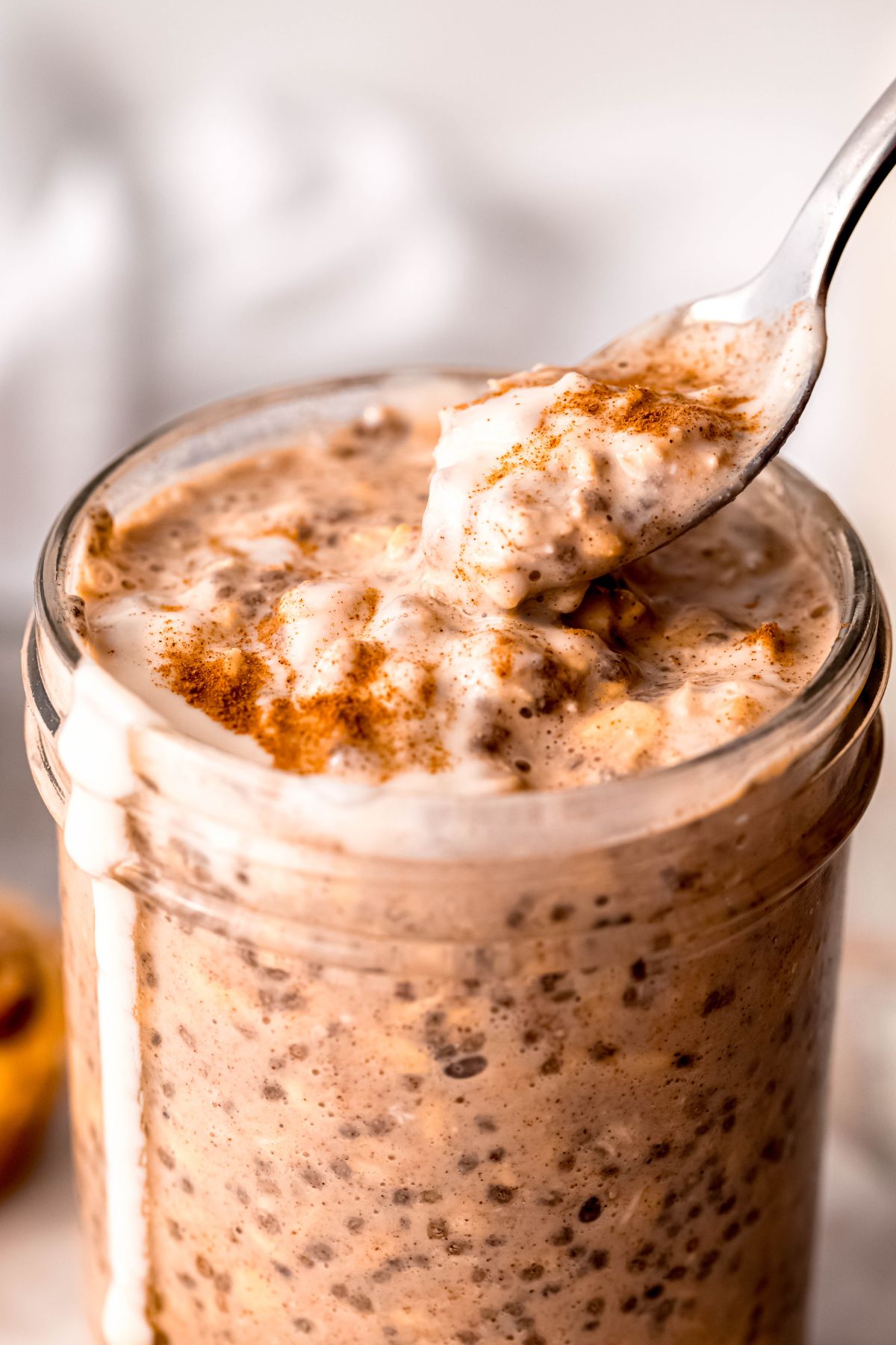 Taking a spoonful of the high-protein cinnamon roll overnight oats from the jar.