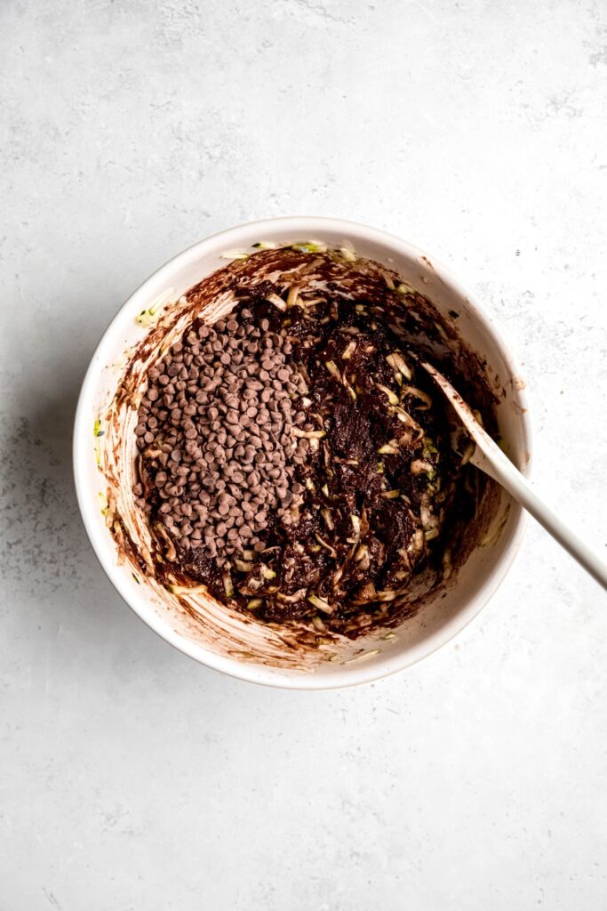 mini chocolate chips added to the mixing bowl with the chocolate zucchini muffin batter.