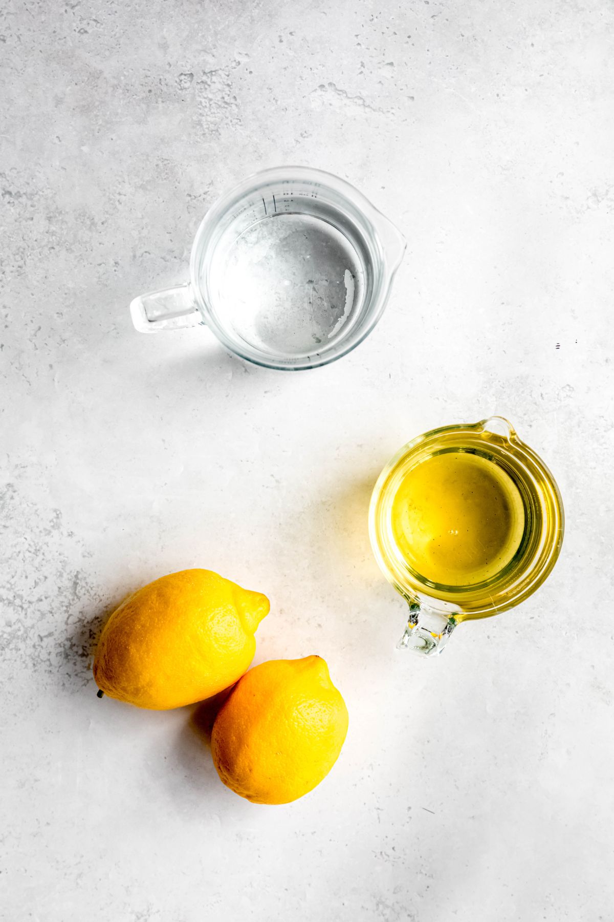 water, whole lemons, and mint syrup measured out for making homemade mint lemonade.