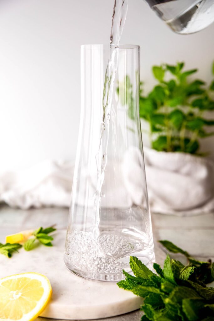 action shot of water being poured into a glass pitcher.
