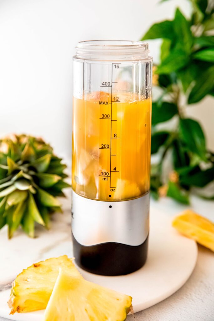 pineapple chunks and pineapple juice added to a blender.