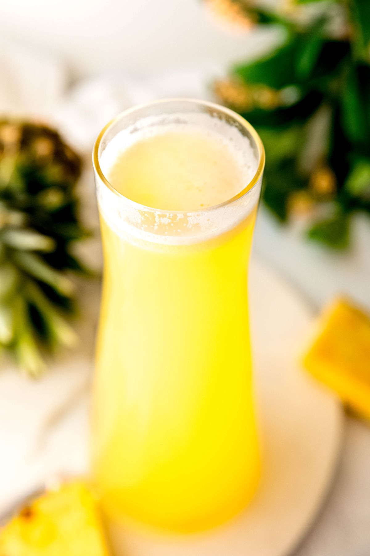 handle-free pitcher filled with homemade pineapple lemonade on a white table.