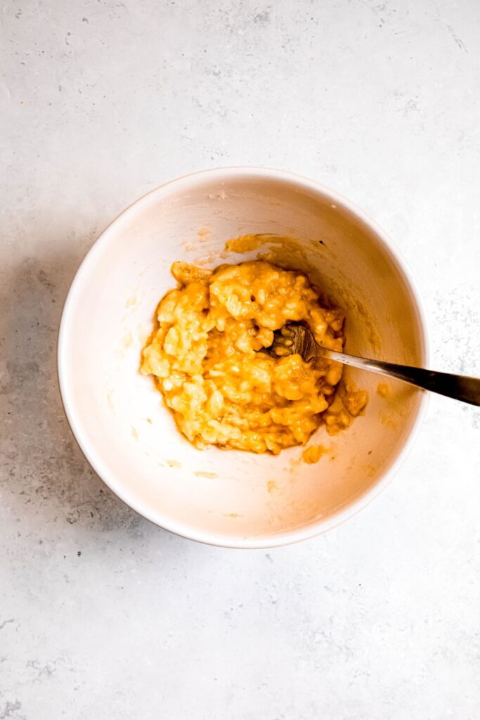 mashed banana in a mixing bowl with a fork.