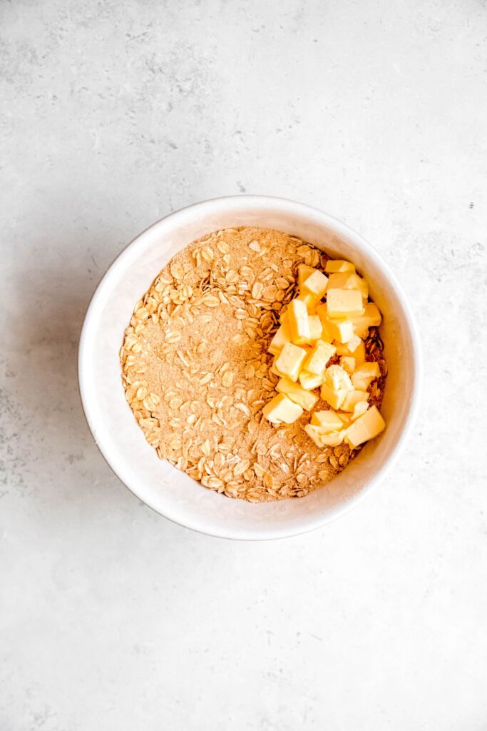 cubed butter added to the bowl with the dry oatmeal crisp topping mixture.