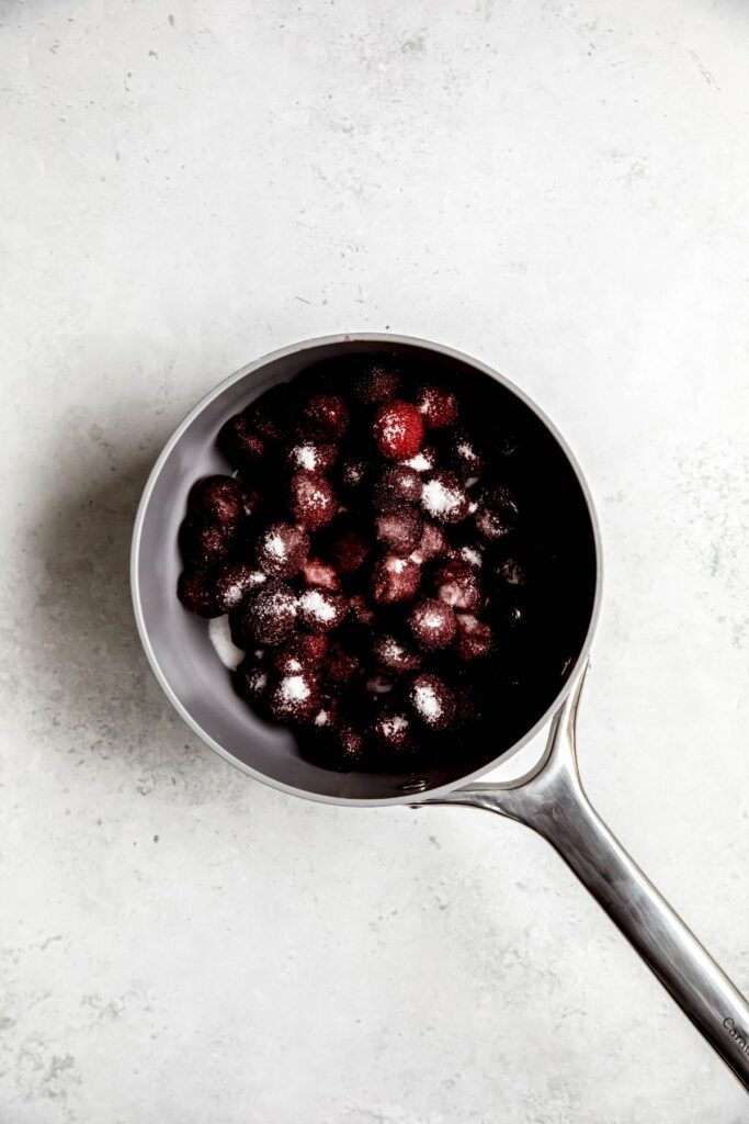 A saucepan of cherries with sugar.