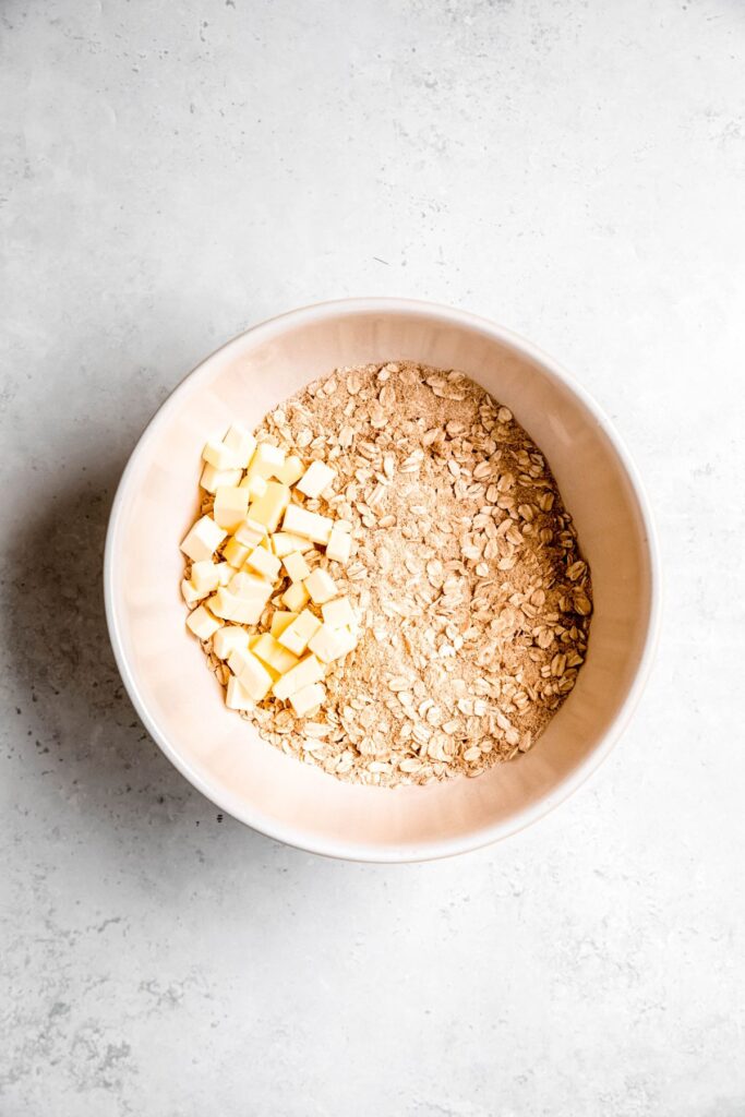A large mixing bowl of the dry ingredients with cubed butter.