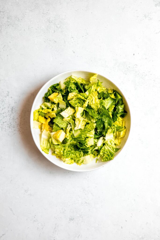 chopped romaine in a white pasta bowl.