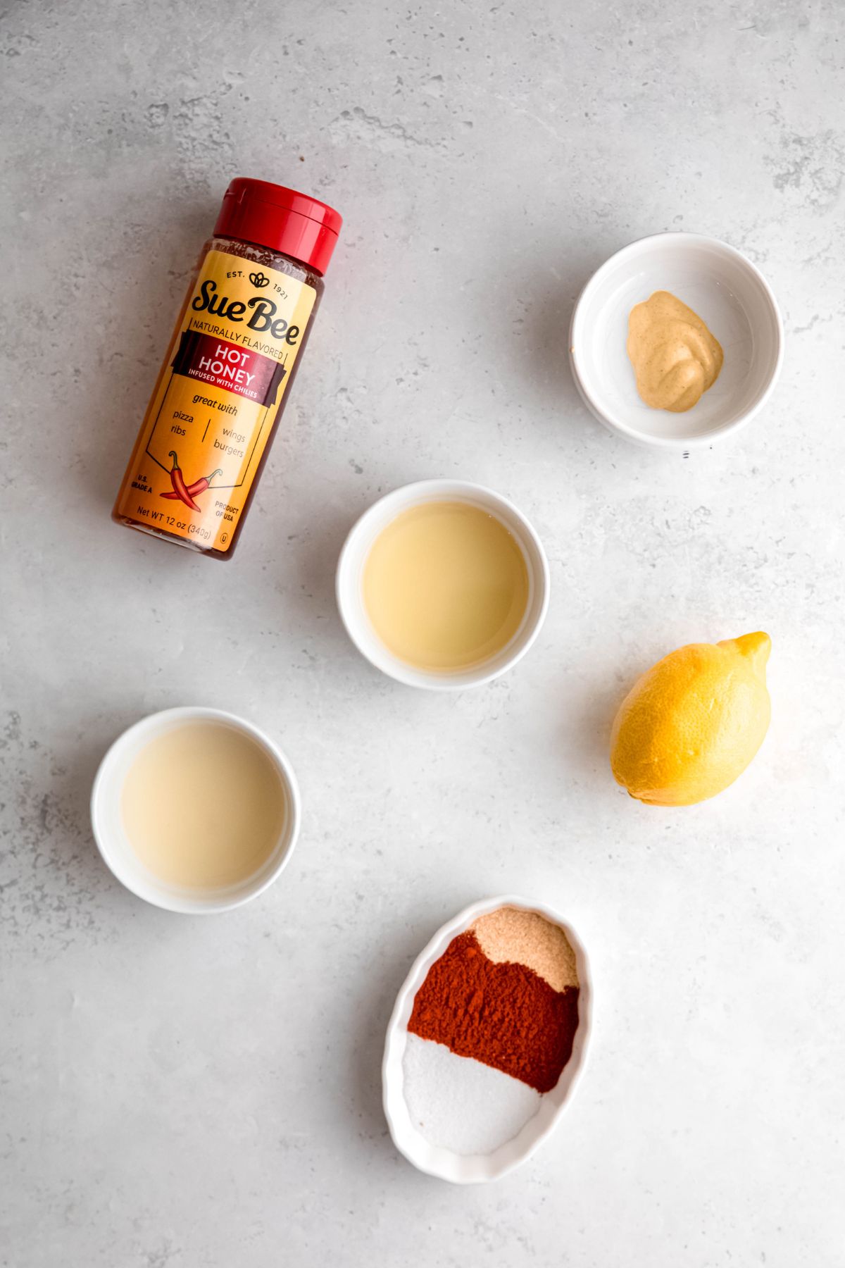 ingredients for making hot honey vinaigrette salad dressing measured out on a white table.