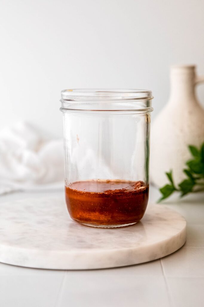 all hot honey salad dressing ingredients added to a mason jar.