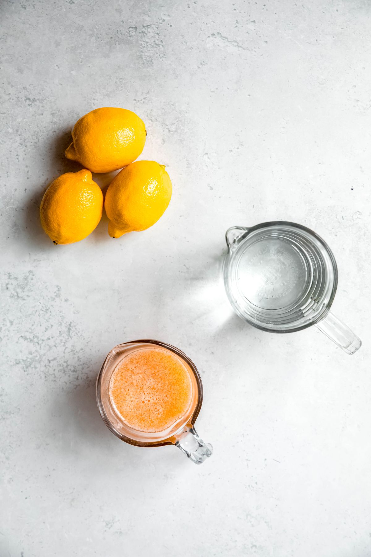 fresh lemons, water, and nectarine syrup measured out on a white table for making homemade nectarine lemonade recipe.