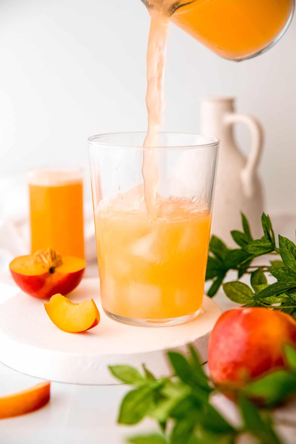 action shot of easy nectarine lemonade being poured into a glass of ice.