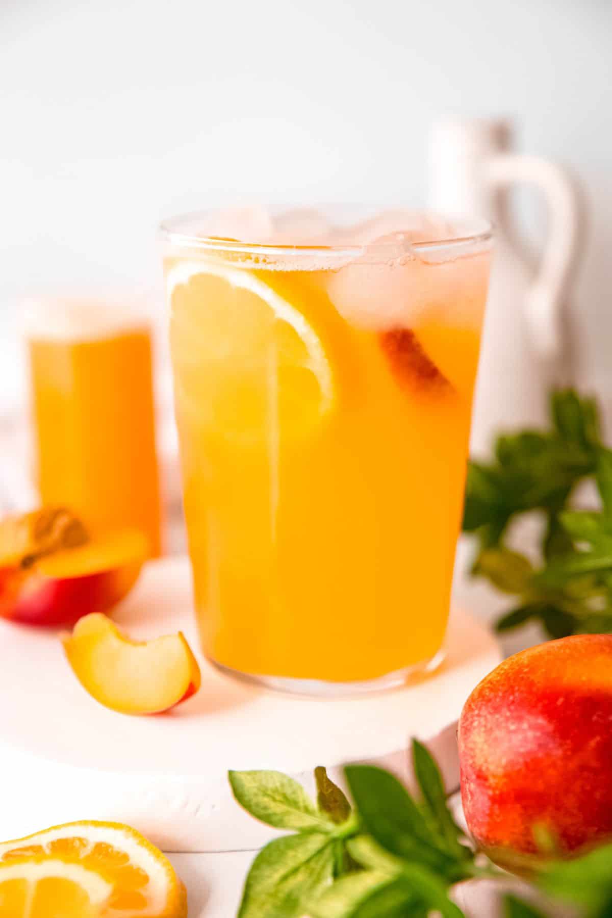 closeup shot of a glass of easy nectarine lemonade with a lemon wheel and a slice of fresh nectarine.