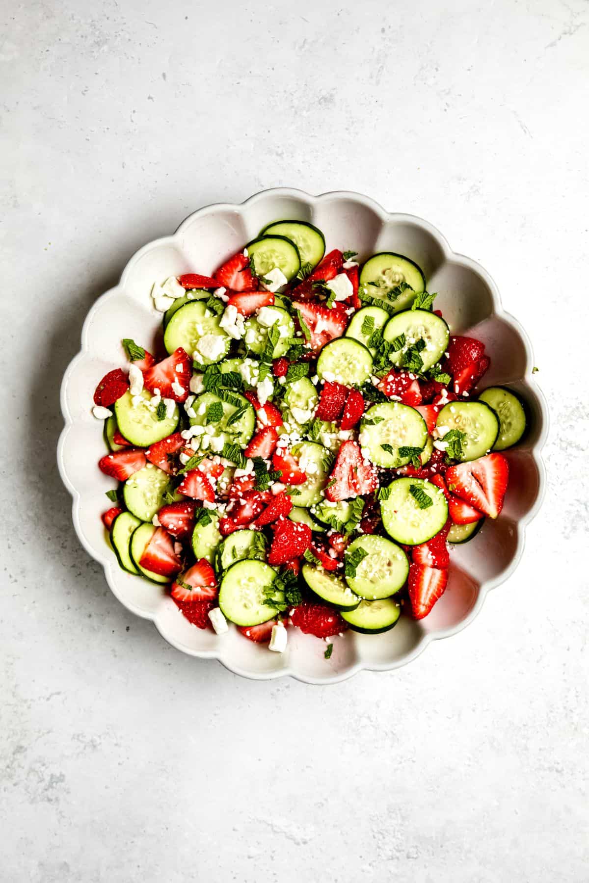 cucumber and strawberry salad after tossing with dressing and topping with feta cheese and mint.