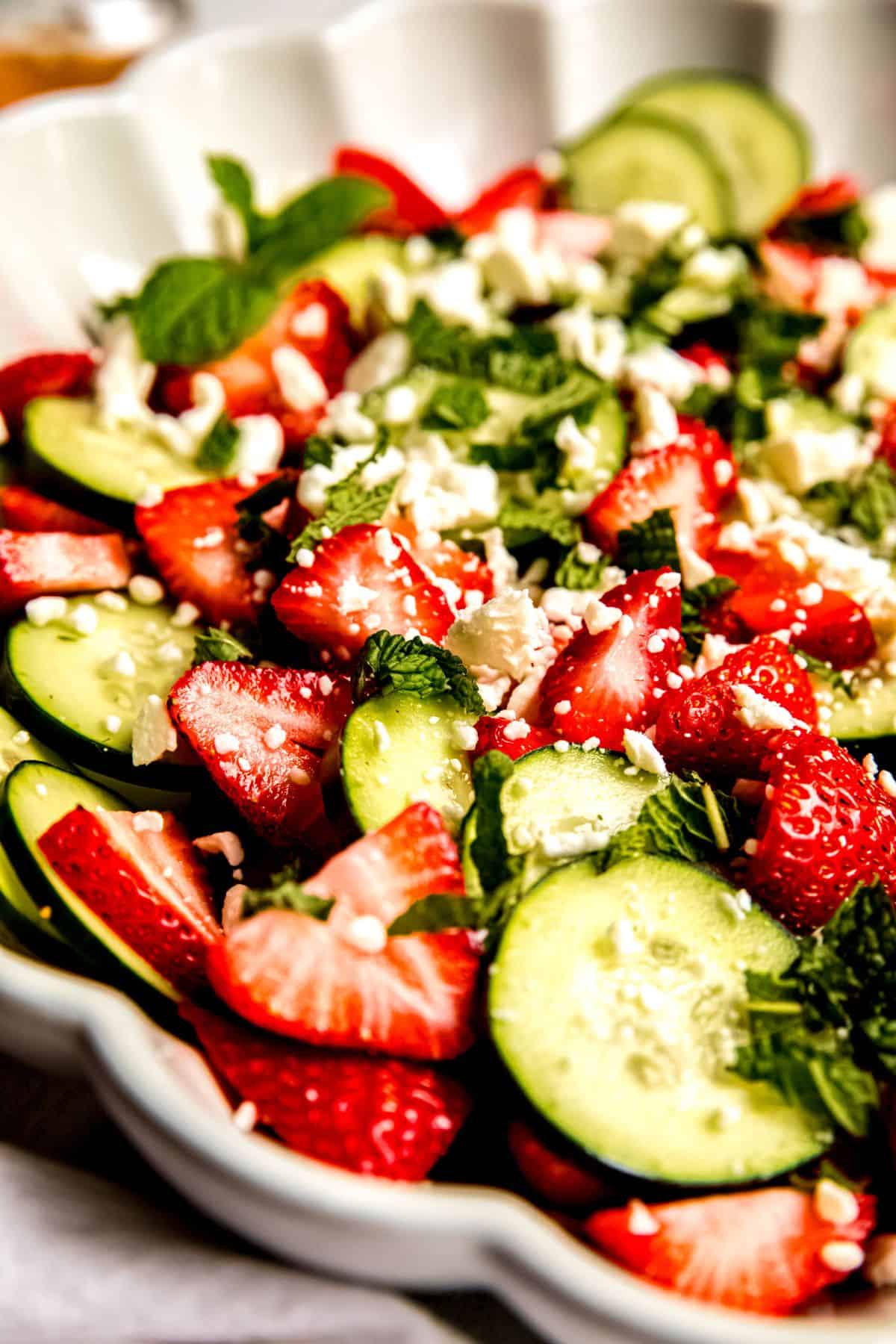 closeup shot of cucumber strawberry salad topped with fresh mint and feta.