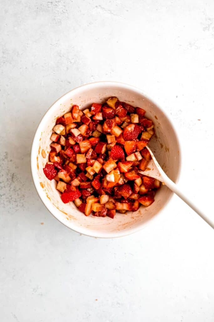 A bowl of rhubarb and strawberries mixed with brown sugar and seasonings.