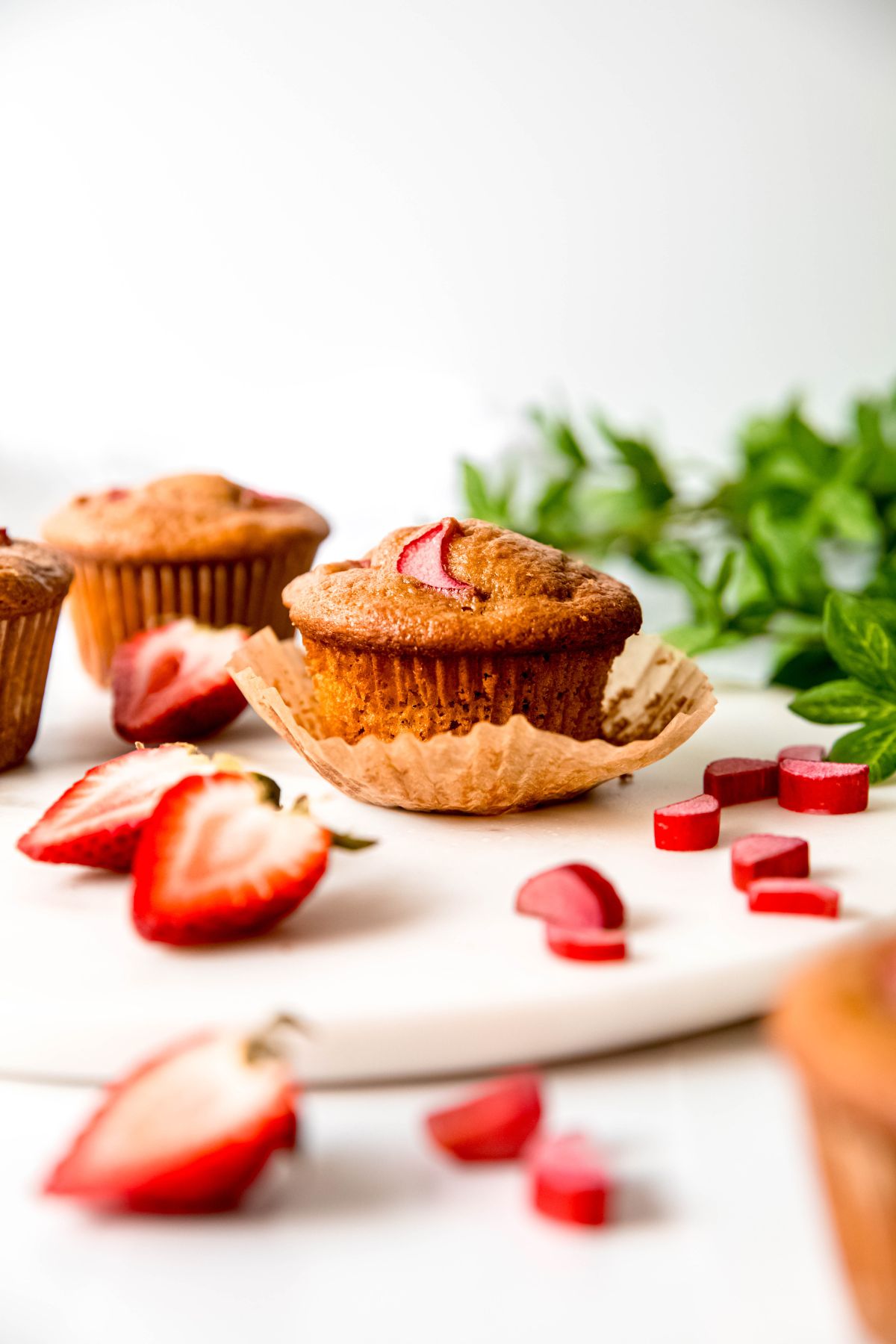 A side shot of an unwrapped strawberry rhubarb muffin on the counter.