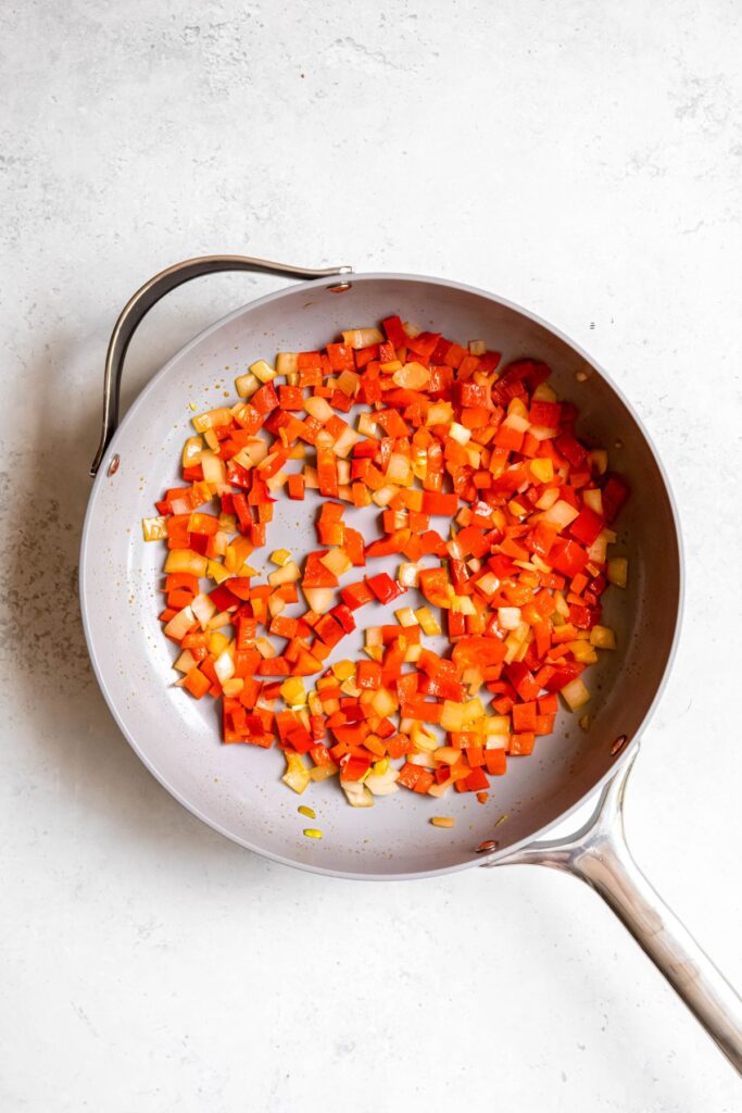 Sauteed onions and peppers in a pan.
