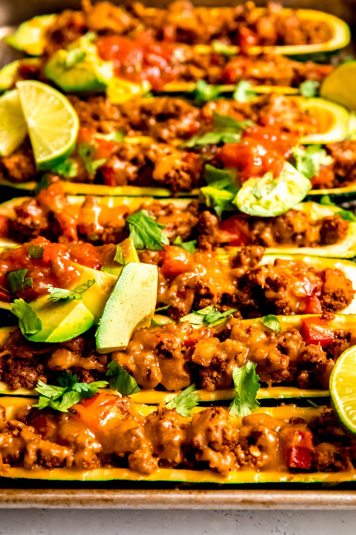A close-up side shot of taco zucchini boats with toppings.