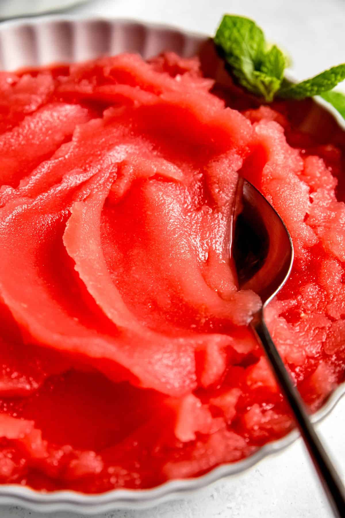 closeup shot of a bowl of homemade watermelon sorbet with a silver spoon.